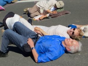 Daniel and Patricia Ellsberg participating in "die in" in the road in front of the Livermore Lab West Gate, awaiting arrest. Photo by Heather Davison.