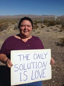 photo of Laura-Marie Taylor (holding a sign quoting Catholic Worker co-founder Dorothy Day, taken by Ming Lai